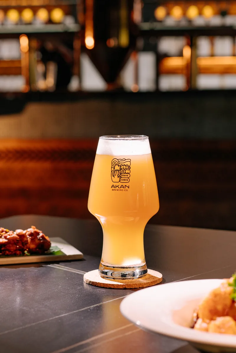 Akan’s branded beer glass alongside dishes from the kitchen